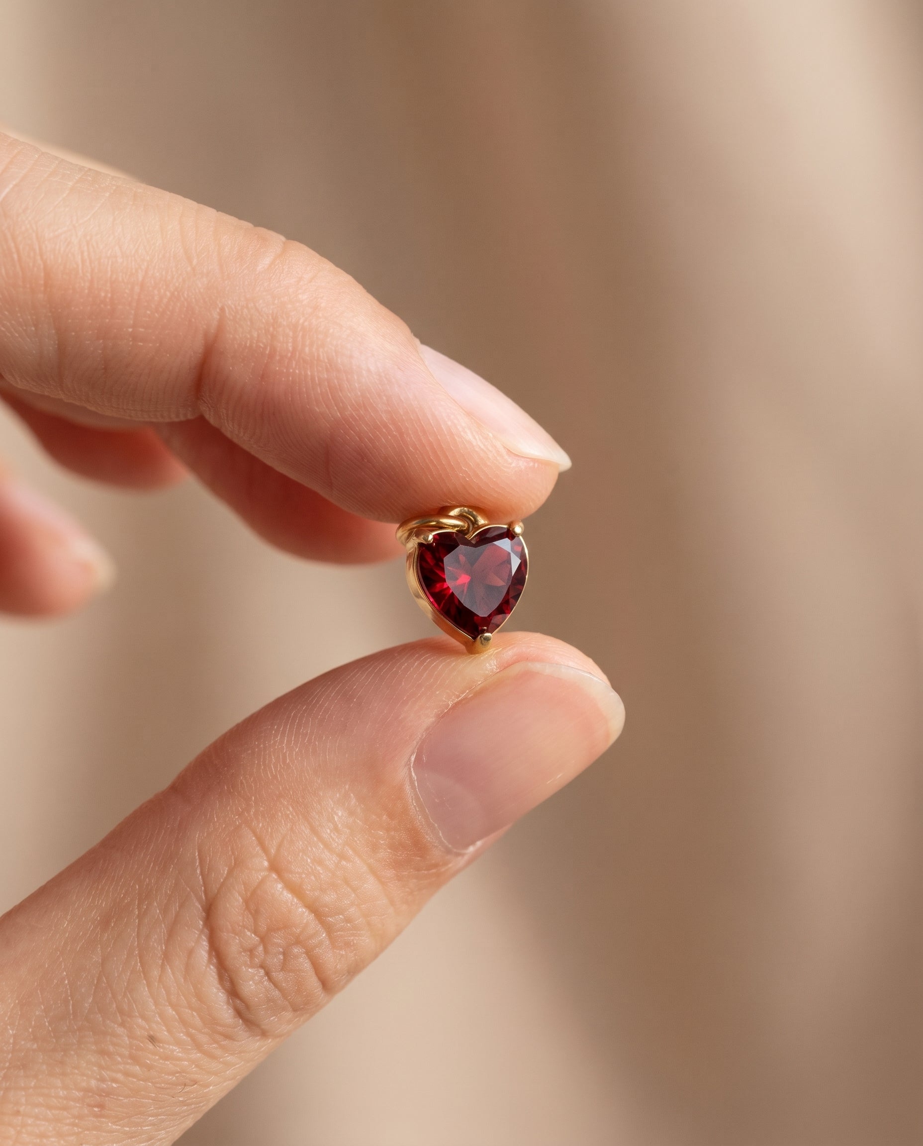 Amour Birthstone Heart Charm in gold held between fingertips