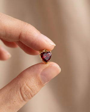 Amour Birthstone Heart Charm in gold held between fingertips