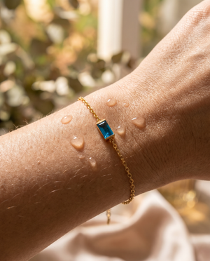 Bianca Birthstone Bracelet in gold on a wrist with water droplets