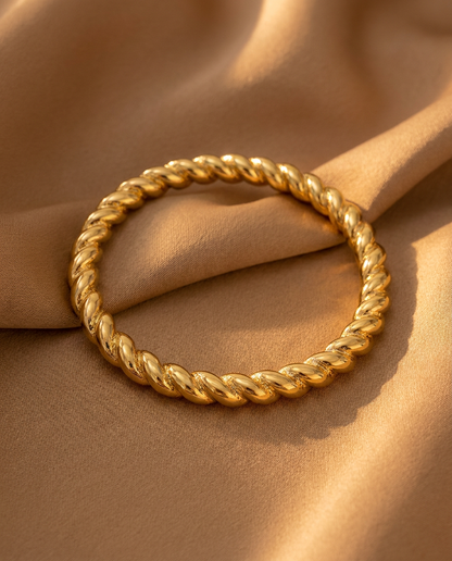Lisa twisted gold bangle resting on camel silk