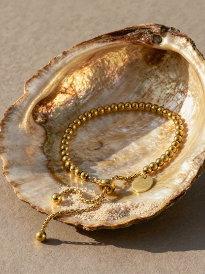 Perla Beaded Bracelet arranged inside an abalone oyster shell with sand